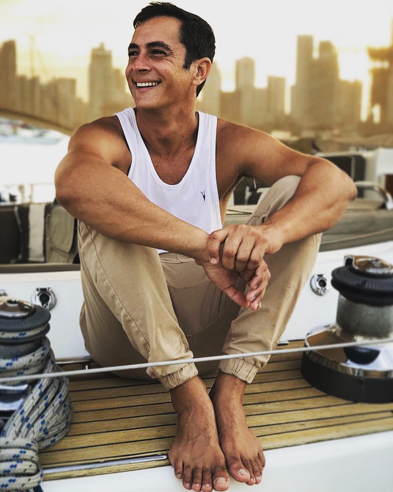 Juan Peña smiling while seated on a sailing boat